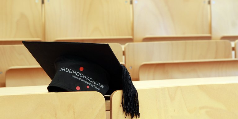 Ein Doktorhut liegt in einem Hörsaal.