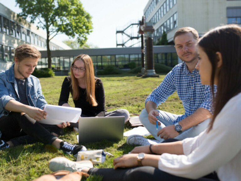 Studierende sitzen auf dem Rasen am Campus Wilhelmshaven