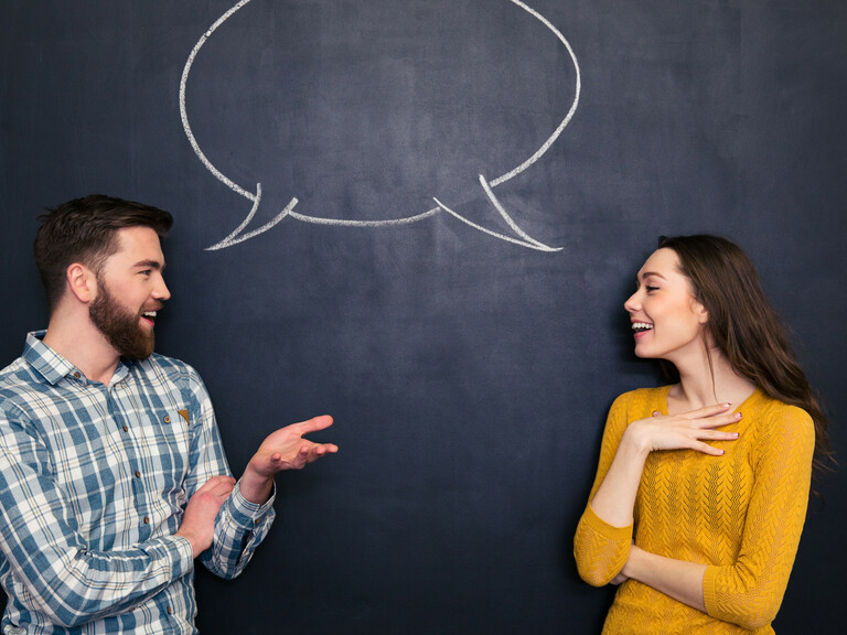 Happy couple talking over chalkboard background with drawn dialogue