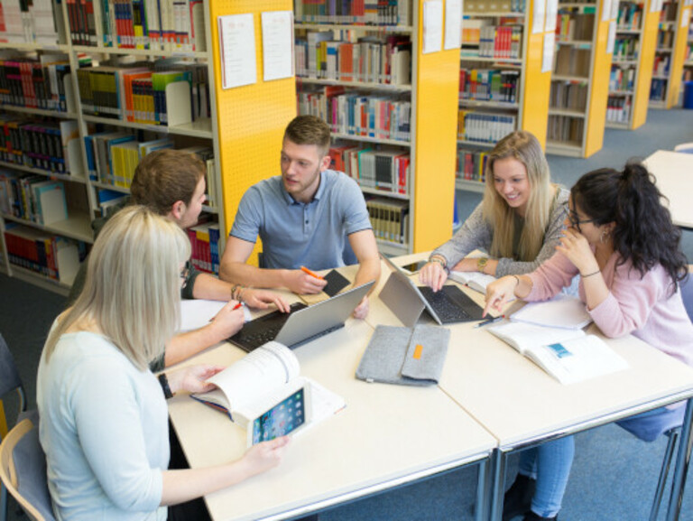 Group of students working at a desk in the Library