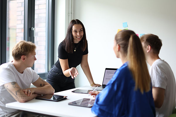 Studentin spricht mit Gruppe von Studierenden