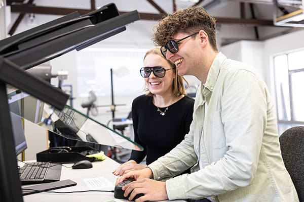 Zwei Studierende blicken Brillen auf Monitor